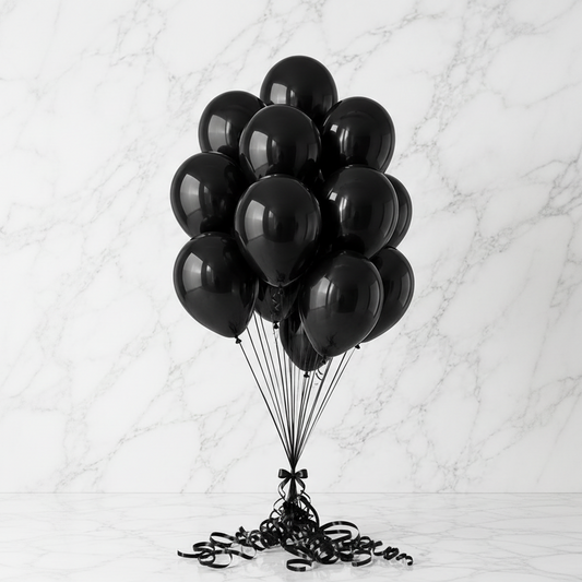 A cluster of glossy black10 helium balloons tied with black ribbons, anchored on a white marble floor against a white marble background.
