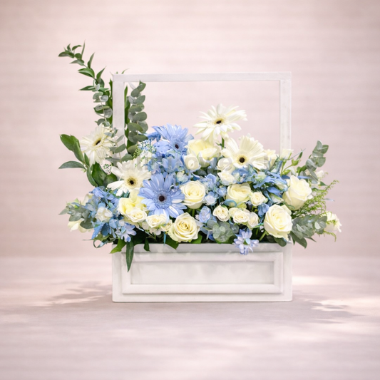 Floral arrangement with blue and white flowers in a white container on a light background