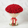 Bouquet of red roses wrapped in beige paper with a red ribbon.