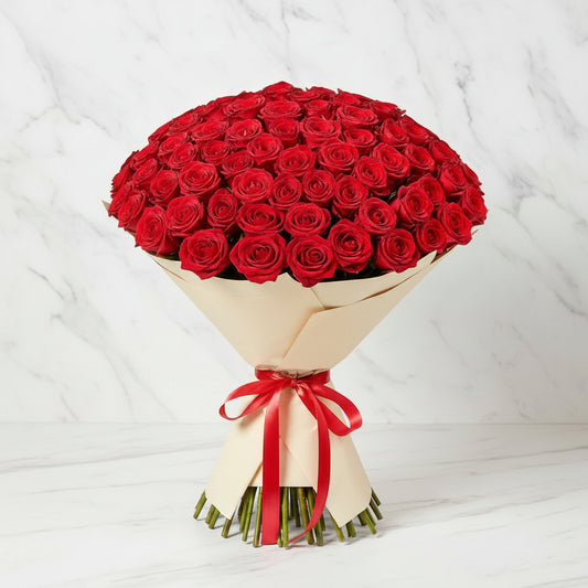 Bouquet of red roses wrapped in beige paper with a red ribbon.