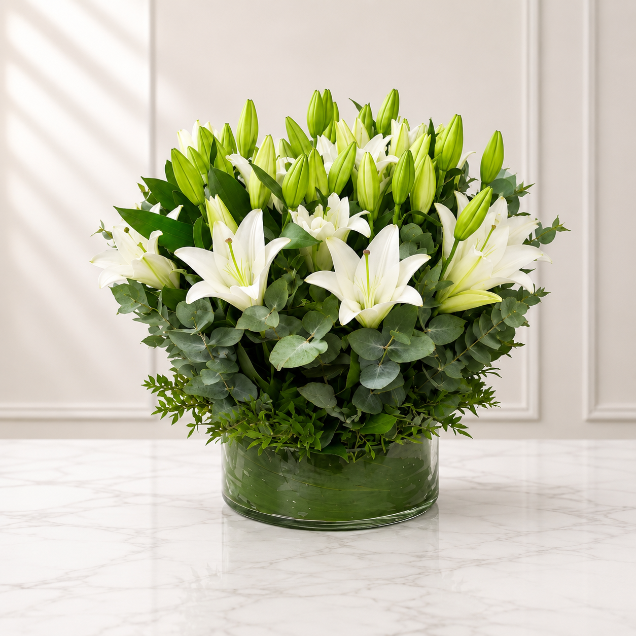 Luxury white lily flower arrangement in clear glass vase with eucalyptus greenery, elegant floral centerpiece by ItalianFlowerKW Kuwait.