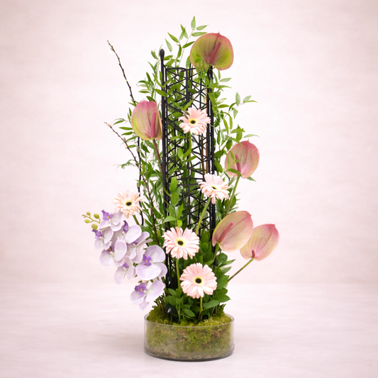 Floral arrangement with a black metal stand on a light pink background.