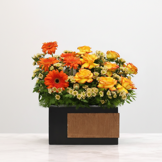 Colorful flower arrangement in a black and wooden box.